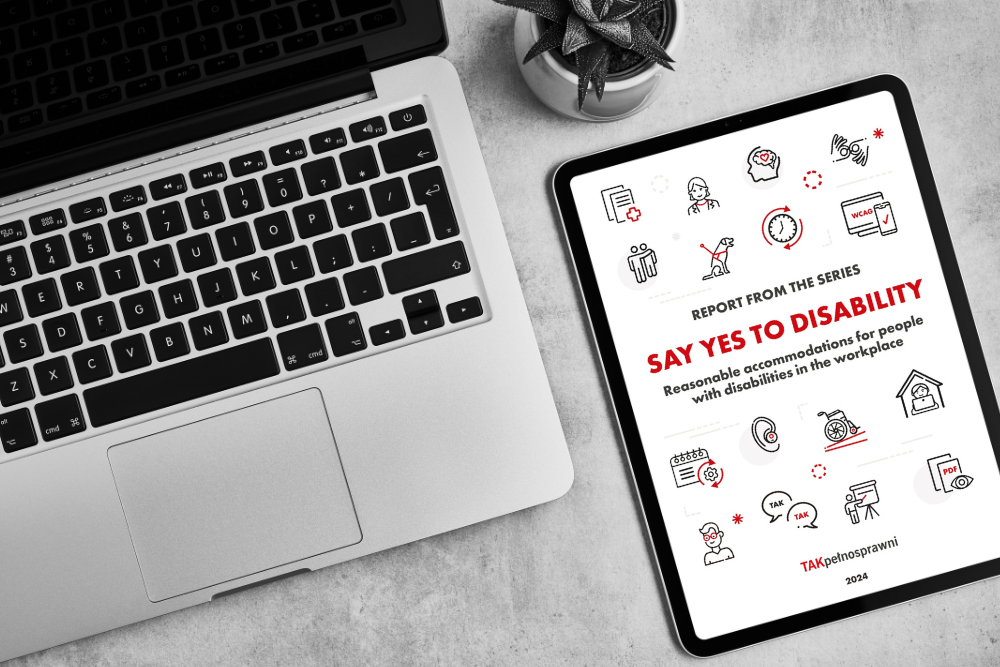 A laptop and tablet on a desk. The tablet screen displays the cover of the report "Say YES to Disability – Reasonable accommodations for people with disabilities in the workplace", featuring icons related to accessibility and inclusion.