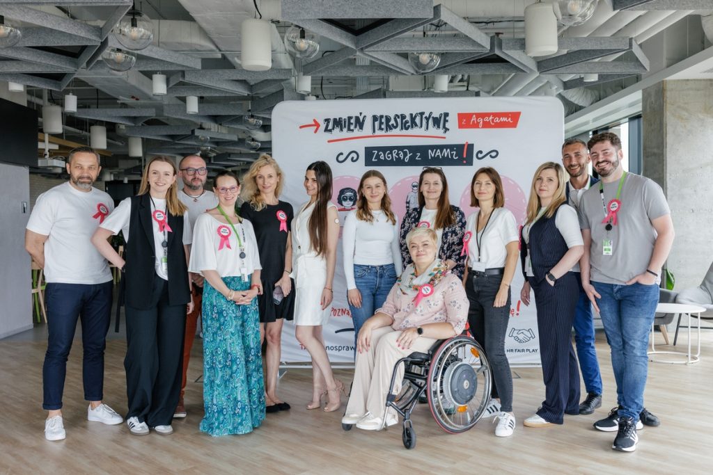 Participants of the “Change Perspective” educational event stand in an office space in front of the event board. In the center, a woman sits in a wheelchair. Group photo of the foundation team and Leroy Merlin Poland employees after the workshop.