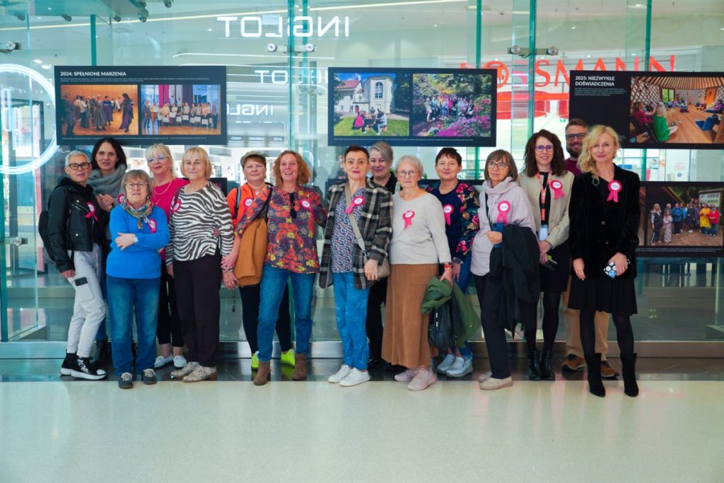 The group of participants in the Breath for Moms project poses together in front of the exhibition boards at the Posnania gallery. In the background are photographs documenting previous editions of the project.